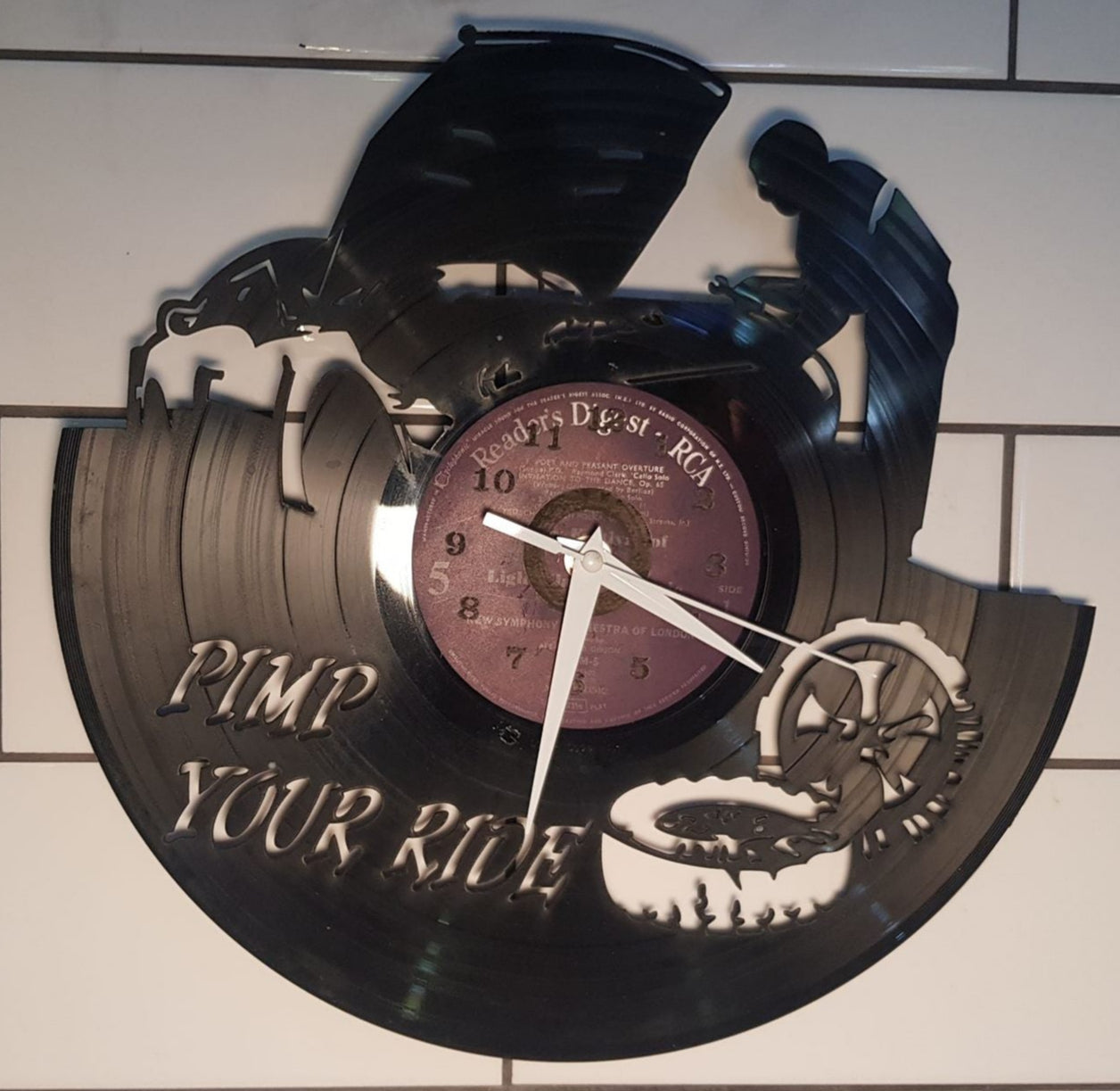 Vinyl record clock with 'Pimp Your Ride' text on a tiled wall