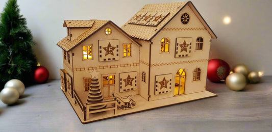 Wooden model house with decorative elements on a wooden surface with numbered advent calendar drawers