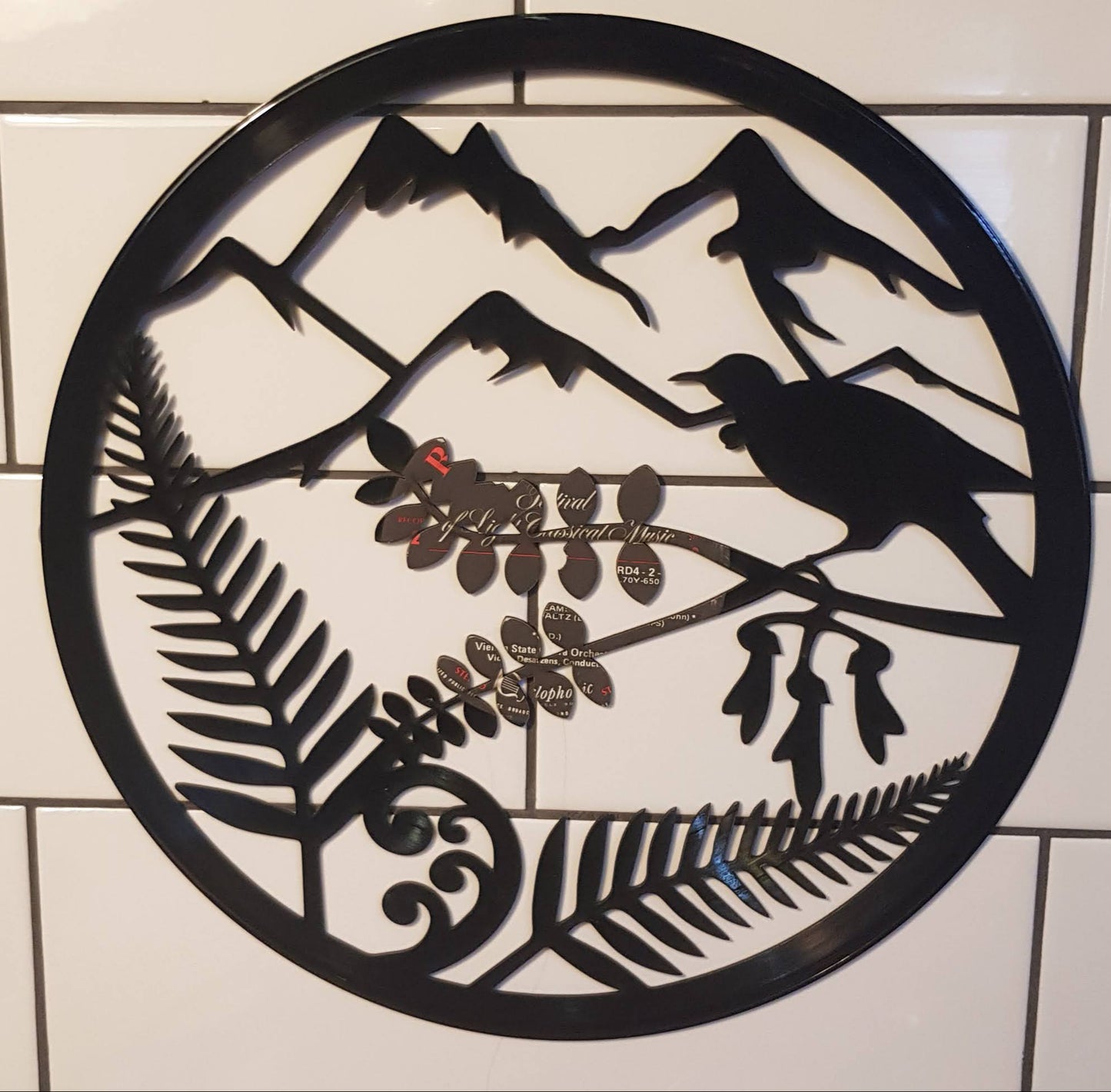 Decorative metal wall art with nature-themed cutouts on a tiled floor.