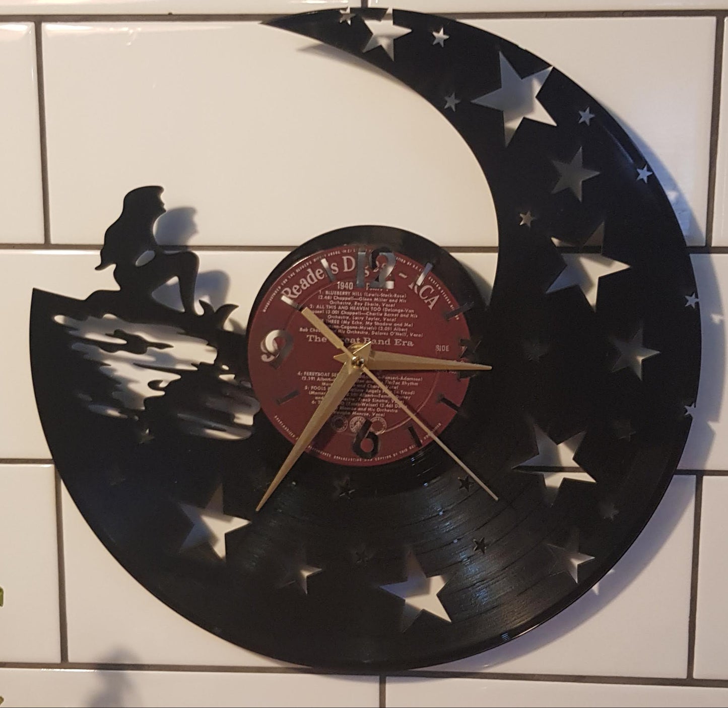 Decorative Little Mermaid clock made from a vinyl record on a tiled wall.