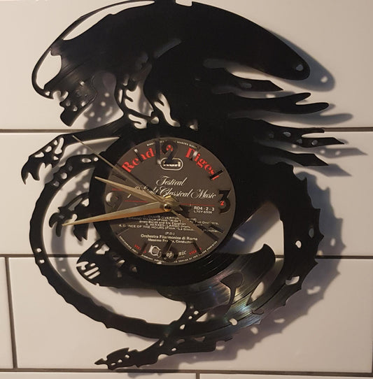 Decorative wall clock shaped like Alien on a tiled wall.