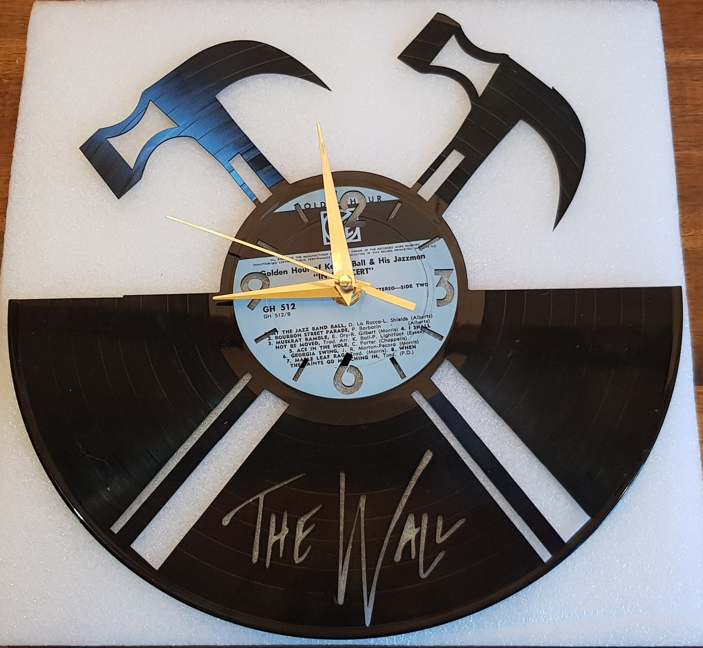 Vinyl record pink floyd the wall clock with a hammer and axe design on a wooden surface