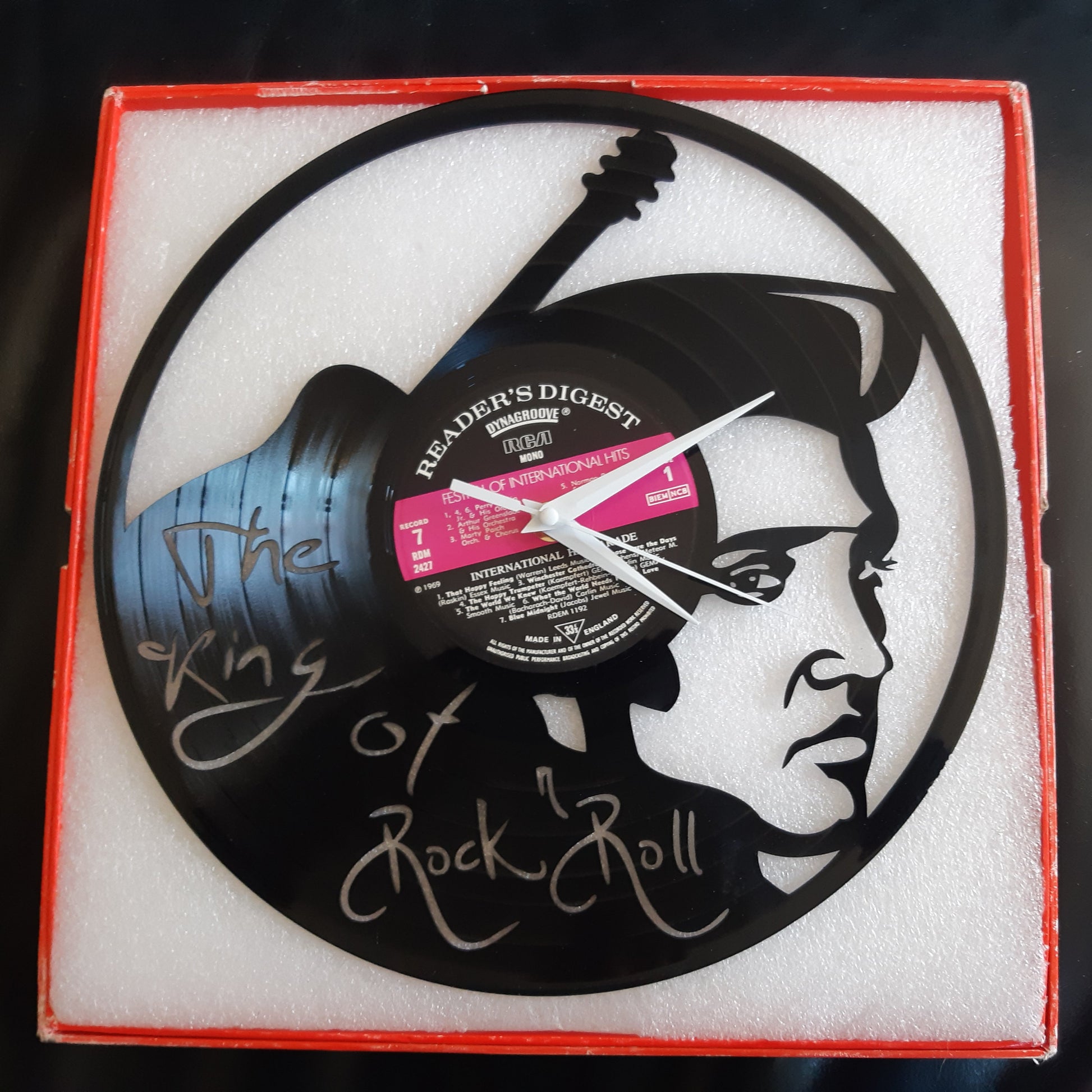 Vinyl record clock with Elvis design and signature on a black surface