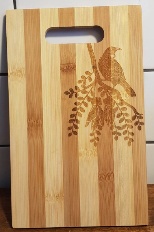 Bamboo cutting board with bird design on a tiled wall background