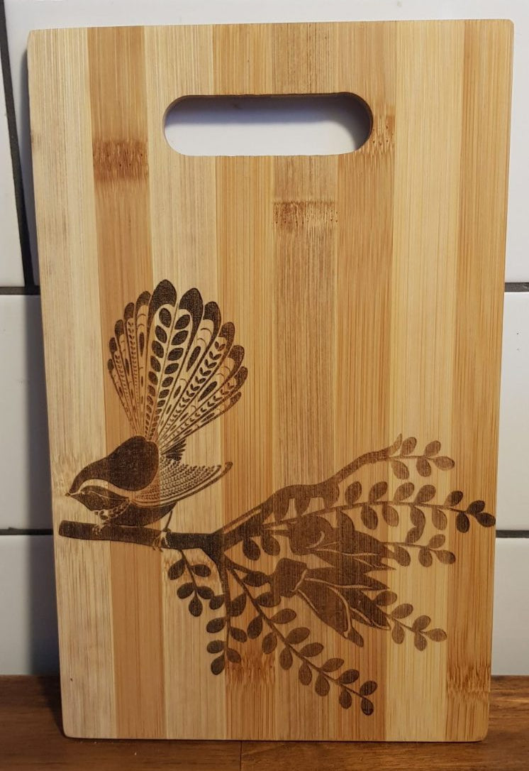 Wooden cutting board with bird and branch design on a tiled wall background
