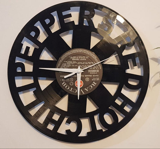 Wall clock made from a vinyl record with The Red Hot Chili Peppers album cover design, placed on a white wall with a plant in the background.
